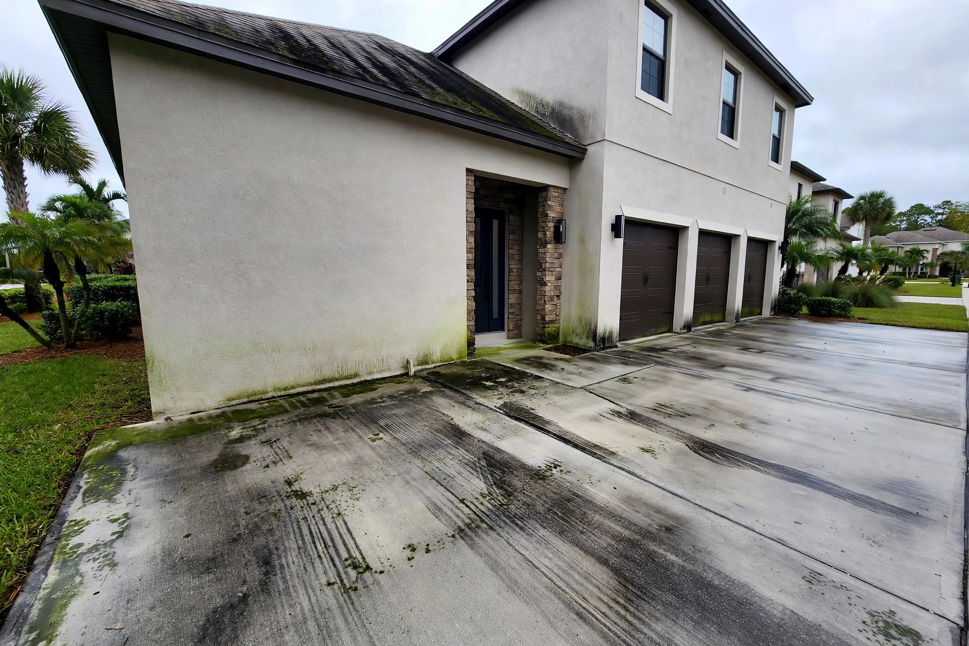 Driveway and home exterior with algae staining before cleaning